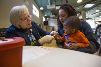 In April 2017, Brandy McGhee holds her two-year-old son Karlton as Sue Taylor pricks his finer to test lead levels in his blood at the Near Northwest Neighborhood Community Center. Staff file photo by Michael Caterina