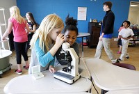 Aliva Tempo, 8, left, and Tatianna Lee, 8, look at slides through a microscope in the new STEM room of the Duneland Boys &amp; Girls Club. Staff photo by Suzanne Tennant