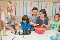 Stephanie Drewry instructs, from left, Eliza Burdick, Addi Kooi, Taylor Potts and Brianna Nelson on filling cupcake liners with batter. (IBJ photo/Daniel Axler)