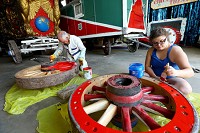 Volunteers Robert Sapita and Morgan Thrasher paint refurbished wagon wheels at the International Circus Hall of Fame in Peru on July 13, 2017. Staff photo by Tim Bath