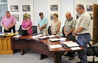Members of the Alexandria City Council bow their heads for a prayer following the Pledge of Allegiance during their meeting on Monday, July 17, 2017. Staff photo by John P. Cleary