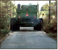Narrow: Phil Ramsey&rsquo;s combine crosses a low bridge, one of two he has to choose between when transporting farm equipment to his fields. The combine&rsquo;s back wheels barely fit within the bridge. At the edge of the bridge, pavement is crumbling because of river overflow. Provided photo