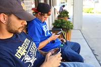 Matt Earnheart and Tristin Capshaw use the free internet service Monday while sitting outside the downtown Kokomo-Howard County Public Library, where WiFi is now available only during business hours for safety reasons. Staff photo by Tim Bath | Kokomo Tribune