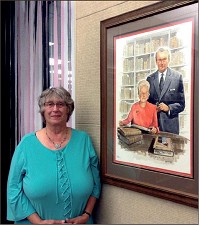 Cindy May, chair of Cunningham Memorial Library's special collections, poses beside a portrait of Warren and Suzanne Cordell, donors of the now world-renowned Cordell Collection of Dictionaries at Indiana State University. Staff photo by Mark Bennett