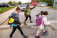 Peggy Fulk helps families cross the intersection of Benham and Wolf avenues Wednesday in Elkhart. The Elkhart City Council voted two weeks ago to remove $222,000 in funding for school crossing guards in 2018. Tribune Photo/MICHAEL CATERINA
