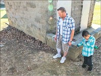 Doug Monroe stands with his son, Javier Molina, as he looks at a discarded needle tip cover Friday in Bloomington&rsquo;s Crestmont neighborhood. Javier, 4, was recently pricked by a used needle he found behind the apartment where he lives. Staff photo by Jeremy Hogan