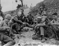 Ernie Pyle, third from left, shares his cigarettes with Marines of the 1st Division at a rest stop along an Okinawa roadside. This photo was taken April 8, 1945, just days before Pyle was shot and killed. U.S. Marines Corps courtesy photo