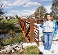 Vicki Kitchen, North Liberty&rsquo;s clerk-treasurer, stands in front of a new walking bridge that spans Potato Creek to link a growing neighborhood with North Liberty Elementary School. Staff photo by Ted Booker