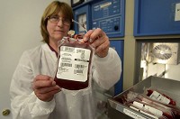  Indiana Blood Center distribution technician Susan Chobanov on Wednesday displays one of the bags of O-negative blood that the center has on hand in one of its refrigerators. O-negative blood, and all blood types, are in need right now.
 Tribune-Star/ Joseph C. Garza