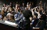 People raise their hands at Tuesday&rsquo;s town hall after Abby Ang, at the podium, asks, &ldquo;who has questions about this purchase?&rdquo; in reference to the city&rsquo;s purchase of an armored vehicle. Staff photo by Jeremy Hogan