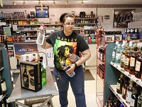 Store manager Tia McGee stocks the shelves at Tower Liquors at 981 S. Creasy Lane in Lafayette. A bill that would allow Sunday alcohol sales is expected to pass next week, but some local liquor stores aren't too happy. Staff photo by John Terhune/Journal &amp; Courier