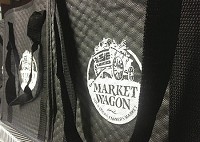 Black and white Market Wagon bags are filled by vendors for distribution to customers.