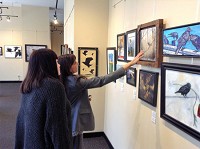 Scanning the artwork: Arts Illiana visitors Sujata Gopalan (right) and Stefanie Pichonnat look at the pieces in the gallery&rsquo;s 2018 Crow Show on Tuesday afternoon. Staff photo by Mark Bennett
