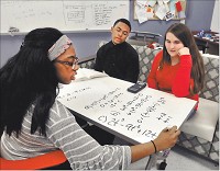 Anderson High School junior Jai Jackson writes down the equation she and classmates, seniors Siraj Elbey and Marissa Merritt, are working on in Richard Ziuchkovski&rsquo;s calculus class on one. Staff photo by John P. Cleary