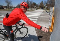 Clay Wilson, of Chicago, presses the traffic signal button at the Erie-Lackawanna Trail where it crossed 45th Avenue in Highland. The trail is seeking several upgrades this year. Staff photo by John J. Watkins