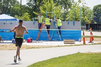 A jogger runs by Thursday as Mishawaka Central Services employees install parts of the new fitness court at Central Park. Staff photo by Michael Caterina