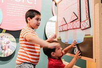 Enzo Davis, 7, and his brother Axel, 2, play with a build-a-bridge, interactive exhibit at the Falls of the Ohio Interpretive Center on Tuesday.&nbsp;| STAFF PHOTO BY JOSH HICKS