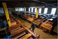 A room on the former Ziker Cleaner campus, now Vested Interest, is filled with pianos waiting to be refurbished by Merriman&rsquo;s Complete Piano Service. Tribune Photo/ROBERT FRANKLIN