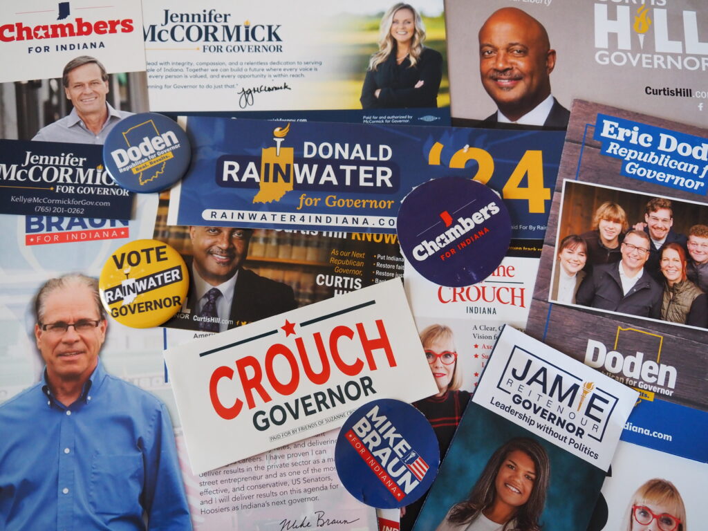  Campaign materials for the 2024 gubernatorial candidates, including the six who weighed in on education priorities. (Whitney Downard/Indiana Capital Chronicle)