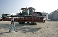 BRIAN SHELBY, 21, walks past a Case combine equipped with a global positioning system.
(Photo by John Terhune, Journal and Courier)