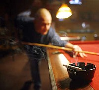 With his cigarette put aside, Mike "Buckeye" Schaefer plays a friendly game of pool in the Hoosier Bar and Grill in Ellettsville Thursday night. A loophole makes Ellettsville exempt from the Monroe County smoking ban. Jeremy Hogan | Hoosier Times