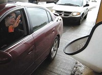 A motorist tosses coins into the change collector on the Indiana Toll Road at the I-65/Dunes Highway exit and entrance. Commutes are likely to become significantly more expensive if the Indiana Toll Road is leased to a private operator. JOHN LUKE | THE TIMES