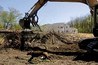 A crew from Perkins Excavating of Valparaiso, which includes Digger the dog, clear land for a tennis and a basketball court in the rear of Portage's first million-dollar home, which is under construction on Samuelson Road. Attorney Robert L. Lewis is building the home. CASEY RIFFE | THE TIMES
