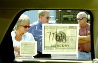 Salesman Bill Paymar, center, shows Jane and Dave Kneller a Mercury Mariner Hybrid at Rice Ford Lincoln-Mercury in Warsaw. Photo by Janelle Sou Roberts/The Journal Gazette
