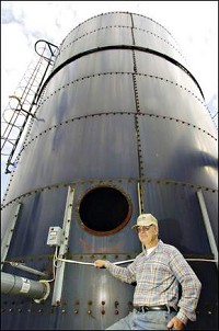 J. B. Cain stands next to the Harvestore silo he converted into dry grain storage outside of Williamsburg. Palladium-Item photo by Joshua Smith