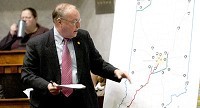 State Sen. Tom Wyss directs the audience to a couple of spots on the map that shows the Indiana Commerce Connector, near Indianapolis, and the Illiana Expressway, near Gary, during a homeland security, transportation and veterans affairs committee meeting Tuesday. PHOTO BY SCOTT ROBERSON