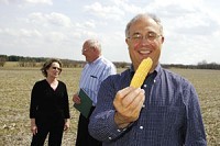Julian Gehman, founder of Blue River Ethanol LLC, holds an ear of corn on the Mount Summit area building site. He hopes by 2009 his plant will produce 100 million gallons of ethanol yearly from corn. Behind Gehman are Betty Gipe, president of the Mount Summit Town Council, and New Castle-Henry County Economic Development Corporation Special Projects Manager Jim Small, who helped prepare the way for the new company. (C-T photo illustration John Guglielmi)