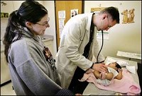 Heather Shepherd (left) looks on as Dr. James Livermore examines her 2-month-old daughter, Yalaina Garrett, at the Tippecanoe Community Health Clinic, 1716 Hartford St. The infant was getting her two-month checkup and shots. By John Terhune/Journal &amp; Courier