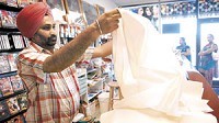 Jimmy Singh, owner of Desi Bazar in Greenwood, measures fabric to be used for a turban. The store is one of several on the southside that sell Indian food and other items. A Croatian-Bosnian grocery store opened recently in Franklin. Photo by Scott Roberson