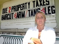 Had enough: Bobbi Weaver, owner of Tan &amp; Trim, who is appealing her new tax bill, stands in front of a sigh advertising new rates for her haircut and tanning services.Photo: Fred Flury / The Truth