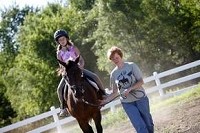 A volunteer helps a child with horseback therapy at the Reins of Life ranch in South Bend where volunteers have cut back on hours. Photographer Janet Graham shot this in a Community Foundation of St. Joseph County project to show the value of what 15 nonprofit agencies do.