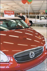 Myers Autoworld salesman Jesse Hughes talks to customer Sandra Carter as she looks over the new Buicks in their showroom. John P. Cleary / The Herald Bulletin