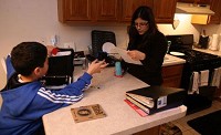 Jessica Gnemi helps her son, Gregory Fontanez, 11, with his homework Wednesday before she cooks dinner at their Hobart home. Gnemi, a Hobart health care worker, said she received her foreclosure papers this Christmas season. JOHN J. WATKINS | THE TIMES