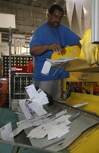 Freddie King dumps letters just unloaded Tuesday from a truck into a machine that will begin the sorting process. The U.S. Postal Service said it is reworking its operations in response to the large drop in mail volume. JOHN J. WATKINS | THE TIMES