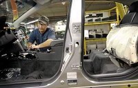 Terry Wade, a production associate, works to install parts into a 2010 Legacy as it roles down the assembly line at the Subaru of Indiana Automotive Inc. factory recently in Lafayette. By Jamie Lynn Chevillet/Journal &amp; Courier
