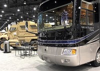 The Monaco RV booth at the National RV Trade Show in Louisville, Ky., featured both recreational vehicles and a military troop carrier. Monaco was purchased out of bankruptcy by Navistar International Corp., which makes a wide range of vehicles. Photo By Tom Fougerousse