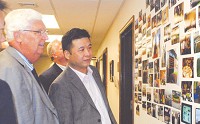 Mayor Leonard Urban (left) shows Zhou Bo, front, and Mark Wastl of Good Times Technology some photos of the Connersville delegation&rsquo;s trip to China in June following Tuesday city council meeting. (DARRELL SMITH / News-Examiner)