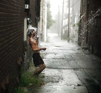 In an alley off Walnut Street, downtown, Travis Puntarelli celebrates a rain storm Sept. 5, following the drought which parched the Midwest during the summer. Rains in September helped ease conditions, but couldn't make up for the dry, dry summer. Jeremy Hogan | Herald-Times