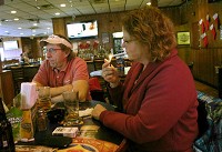Terri Schiesser of Crown Point (right) lights a cigarette at Sheffield's with Ron Schiesser (left) and friends in Merrillville, Ind. Thursday January 3, 2012. Since the passage of new smoking laws, Sheffield's, both the restuarant side and sports bar side, has become a 21 years old and over establishment in order to allow smoking. | Stephanie Dowell~Sun-Times Media