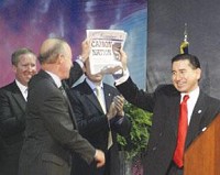 Carbon Motors CEO William Santana Li (right) and Indiana Gov. Mitch Daniels hold up a copy of the News-Examiner after their announcement on July 29, 2009, that the company would locate in Connersville. (GRADY TATE / News-Examiner file photo)