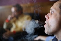 Cigar Lounge employee Chris Hoch, of St. John, smokes a cigar with customers and co-workers at the store in Schererville. Indiana has a smoking rate of 24 percent, which is higher than the national average of 19.6 percent, according to the Indiana State Department of Health. Staff photo by Jonathan Miano