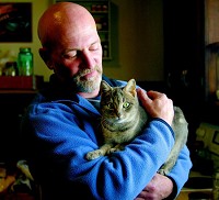 Brian Hudson, a former meth user, is going through drug court and getting his life back together. Hudson, here with his favorite cat, Nanny, lives with five cats in a small home in Alexandria. Staff photo by John Cleary