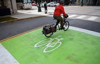 A bicyclist rides through a bicycle-friendly zone in downtown Bloomington in this file photo from Oct. 23, 2013. This bike box near Seventh and Walnut streets allows for bicyclists to stop at the front of the line of vehicles in a green safe zone to prepare for a turn in the next block. Cars are to stop at the solid white line behind the green zone while at a stoplight. Staff photo by Chris Howell