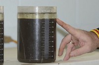 This beaker shows the separation of water from sludge. By repeating the mixing and settling process several times, a higher concentration of sludge is created. Staff photo by Jim Avelis