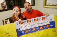 Bailey Flick, a senior at Bloomington High School North, and guidance counselor Greg Chaffin display the Hands Against Homophobia sign that hung for most of the year in the library at North. Chris Howell | Herald-Times