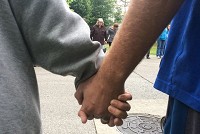 Two people hold hands at a Scott County prayer walk sponsored by Together For Scott County: From Darkness to Deliverance (T4SC). The Monday prayer walks, which began in April in response to the area&rsquo;s HIV outbreaks, have brought out hundreds of people to walk through Scott County neighborhoods and pray over their residents. Staff photo by Danielle Grady